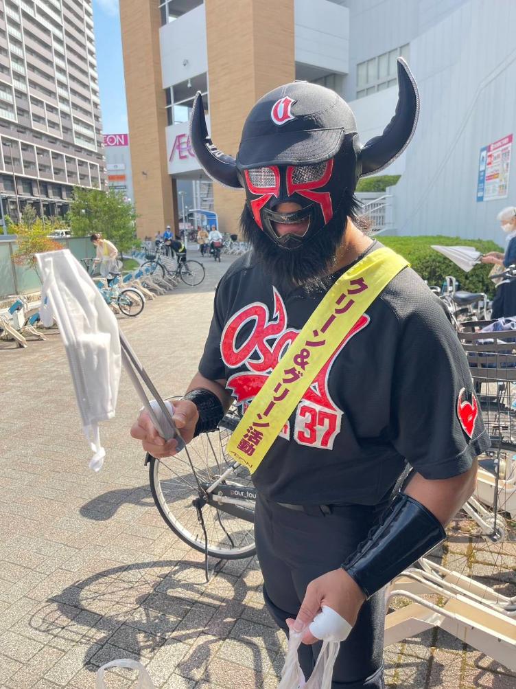 火バサミで落ちているマスクを拾い上げるブラックバファロー